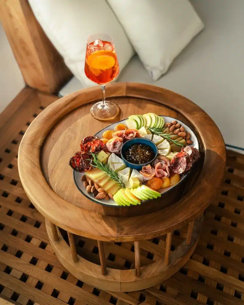 Charcuterie platter and Aperol spritz served on a wooden deck table on board