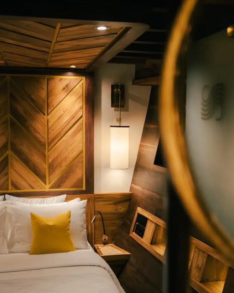 Wood-paneled cabin with herringbone headboard and warm ambient lighting on board Otium