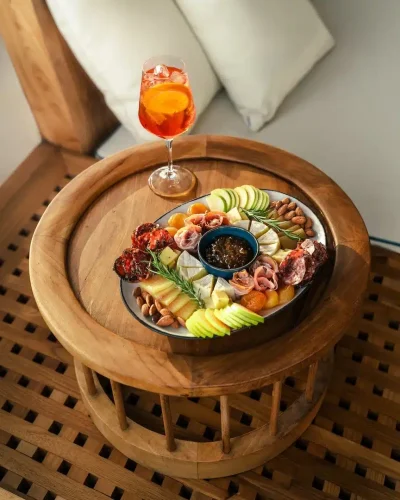 Charcuterie platter and Aperol spritz served on a wooden deck table on board